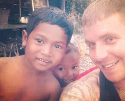 Man and 2 children smiling into camera, taking a selfie.