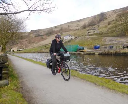 Man on a bicycle riding on a pathway near a canal